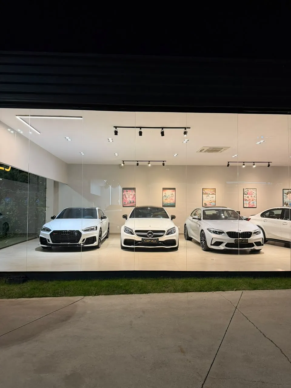 Vitrine da Cenci Motors à noite com três carros brancos expostos lado a lado