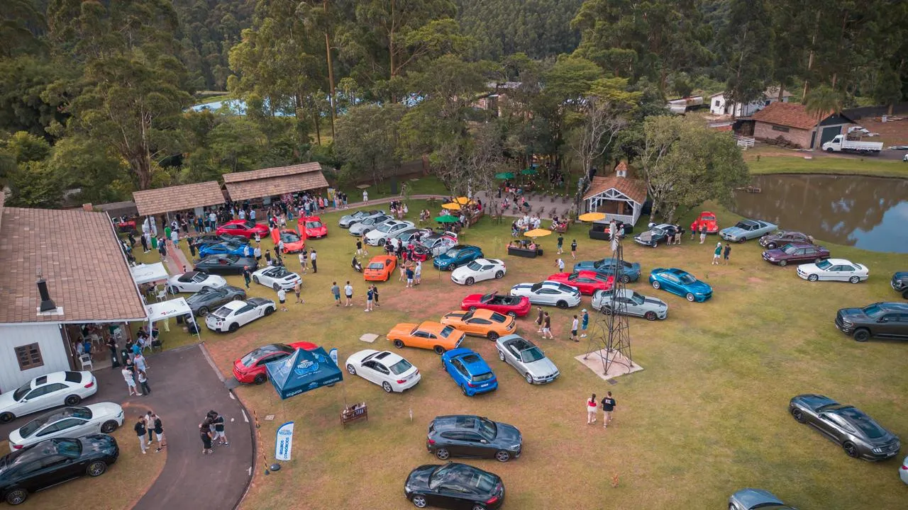 Vista do alto do gramado do evento, cheio de carros e de visitantes