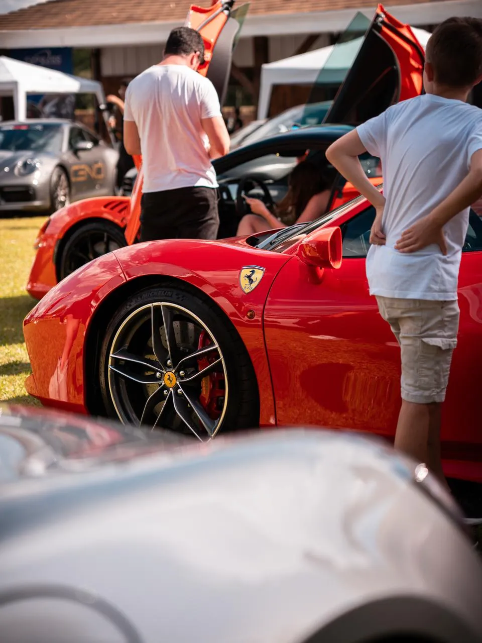 Ferrari vermelha com as portas abertas e visitantes olhando de perto, em uma edição anterior